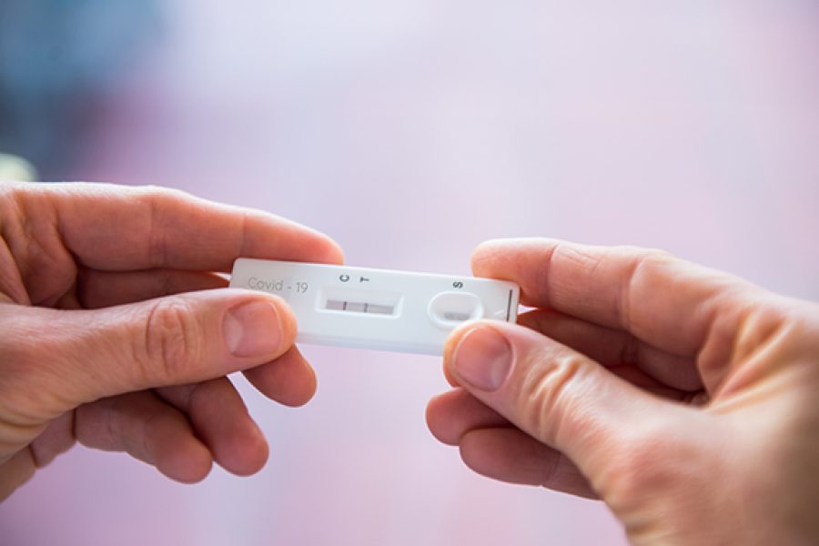 Close up woman hands holding rapid covid -19 test with a positive result. Self express coronavirus testing at home. Covid-19 test kit for detecting IgM IgG antibodies and immunity. Selective focus